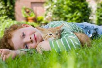 Un garçon tenant un chaton — Photo de stock