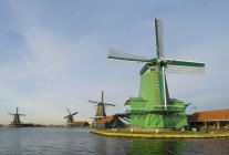 Fila de moinhos de vento contra céu nublado em Zaanse Schans, Zaandam, Países Baixos — Fotografia de Stock
