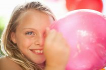 Sonriente chica sosteniendo globo en fiesta - foto de stock