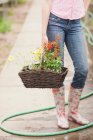 Zugeschnittenes Bild einer Frau, die einen Blumenkorb in der Gartenmitte trägt, niedriger Schnitt — Stockfoto