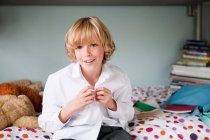 Jovem menino abotoando sua camisa da escola em seu quarto — Fotografia de Stock