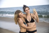 Donne che si abbracciano e si scattano selfie con il cellulare sulla spiaggia, Amagansett, New York, USA — Foto stock