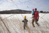 Padre caminando con dos hijos en el paisaje cubierto de nieve - foto de stock