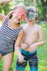 Portrait of boy and girl in garden wearing swimming goggles — Stock Photo