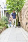 Padre e hijo paseando perro en camino - foto de stock