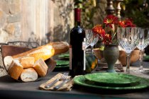Brot und Weinflasche am gedeckten Tisch — Stockfoto