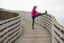 Runner stretching on wooden dock — Stock Photo
