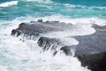 Surfen über Felsen am Strand von Muriwai — Stockfoto