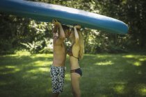 Romantic mature man kissing girlfriend whilst holding up kayak in garden — Stock Photo