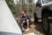 Young man erecting tent in forest, Lake Tahoe, Nevada, USA — Stock Photo
