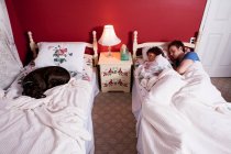 Junges Paar teilt sich Einzelbett, Hund schläft auf anderem Bett — Stockfoto