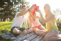 Young group of friends drinking and celebrating in park — Stock Photo