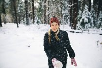 Donna nella foresta innevata gettando neve dalla tazza — Foto stock