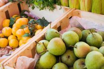 Poires et prunes sur étal de fruits — Photo de stock