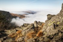 Nubes bajas y pico rocoso de montaña a la luz del sol - foto de stock