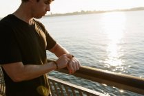 Чоловік бігун на березі річки перевіряє свій годинник — стокове фото