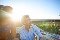 Молодая пара сидит на солнечном балконе и улыбается — стоковое фото