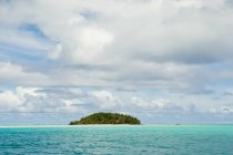 Green island in pacific ocean under cloudy sky — Stock Photo