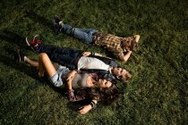 Пара и друг лежат на траве ночью под высоким углом — стоковое фото