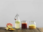 Fruit smoothies in glass bottle and jars, white background — Stock Photo