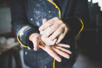 Обрізаний вид середнього дорослого чоловіка, що стискає глину в руках — стокове фото