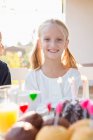 Retrato de menina feliz com bolo de aniversário na mesa do pátio — Fotografia de Stock