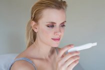 Junge Frau schaut sich Schwangerschaftstest an — Stockfoto