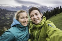 Giovane coppia di escursionisti che scatta l'autoritratto, scendendo dal monte Zinken, Oberjoch, Baviera, Germania — Foto stock