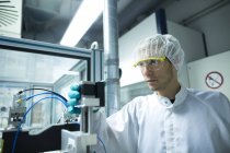 Чоловік-вчений дивиться на обладнання в лабораторній чистій кімнаті — стокове фото