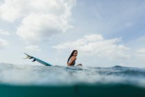 Oberflächenansicht einer Frau auf einem Surfbrett, die in die Kamera schaut, Oahu, Hawaii, USA — Stockfoto
