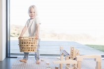 Niño llevando cesta de bloques de madera - foto de stock