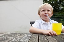 Молодий хлопець п'є сік з соломою — стокове фото