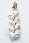 Spicchi d'aglio freschi tessuti su superficie bianca — Foto stock
