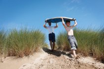 Отец и сын несут доску для серфинга — стоковое фото