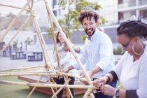 Colleagues in team building task building wooden structure smiling — Stock Photo