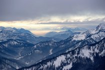 Montanhas alpinas cobertas de neve com céu nublado ao pôr do sol — Fotografia de Stock