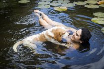 High angle view of young woman with dog floating among lily pads smiling, Taiba, Ceara, Brazil — Stock Photo