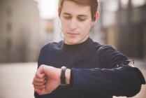 Молодий чоловік бігун перевіряє наручний годинник на міській площі — стокове фото