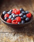 Fresh raspberries and blueberries in a wooden bowl, close up — Stock Photo