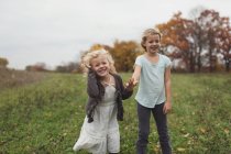 Duas irmãzinhas brincando juntas no campo verde na temporada de outono — Fotografia de Stock