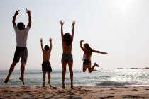 Familie springt am Strand in die Luft — Stockfoto