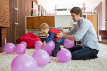 Pai e filho brincando com balões na sala de estar — Fotografia de Stock