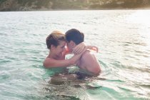 Sonriente pareja abrazándose en el agua - foto de stock