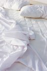 Sábanas arrugadas en la cama en el dormitorio - foto de stock