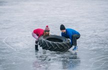 Пара перекидає шини на замерзле озеро — стокове фото