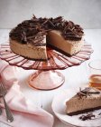 Shocolate cheesecake on pink cakestand and slice on plate — Stock Photo
