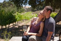 Молодая пара в винограднике, женщина с белым вином — стоковое фото