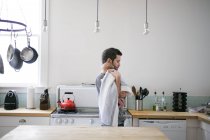 Середній дорослий чоловік, що носить дитячого сина на кухні — стокове фото