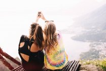 Rückansicht zweier Freundinnen beim Smartphone-Selfie am Atitlan-See in Guatemala — Stockfoto