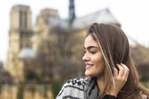 Side view of young woman, Notre Dame Cathedral in background, Paris, France — Stock Photo
